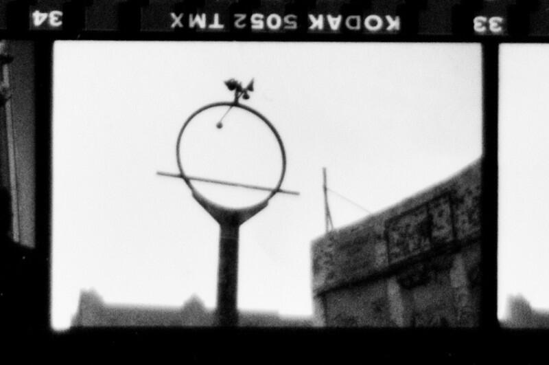 Photograph of a proof sheet showing a grainy, black-and-white photograph of an empty, derelict gas station sign.